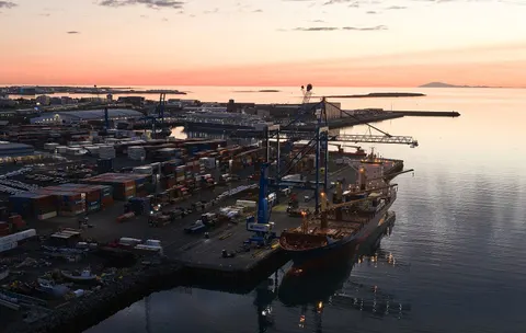 Container port with ship and stacked containers at dusk