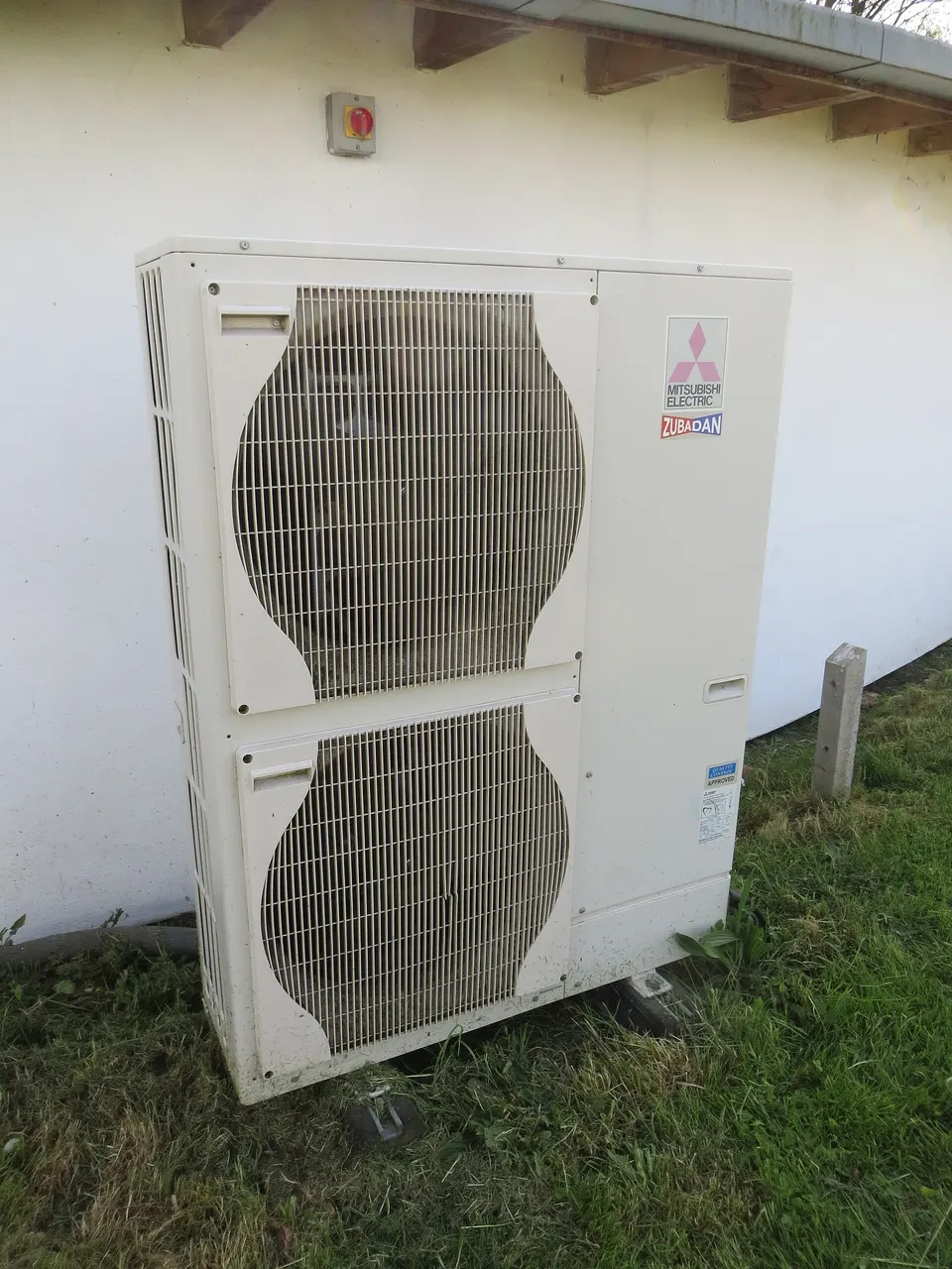 Air-source heat pump outdoor unit beside a house